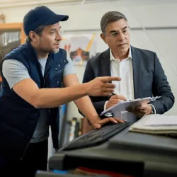 mid-adult-manager-car-mechanic-talking-while-using-computer-auto-repair-shop